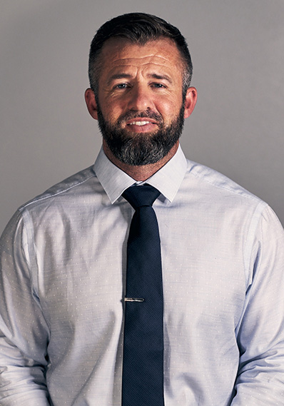 A man with a beard in a blue shirt and tie.