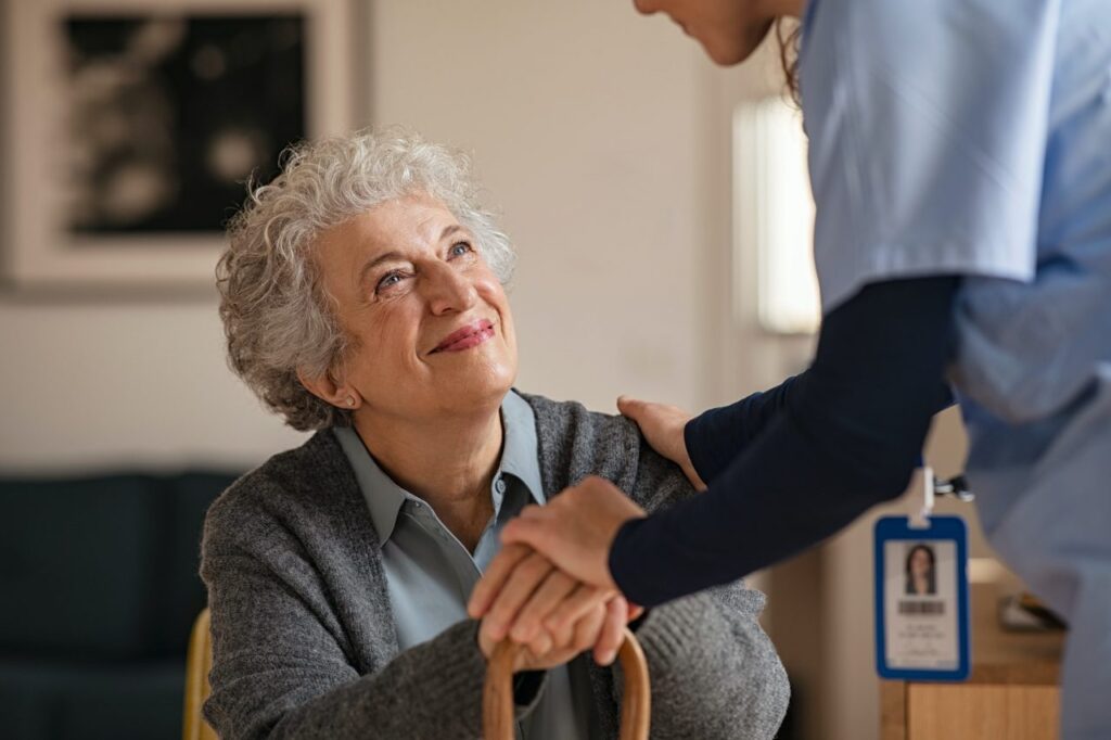 A nurse shakes an elderly woman's hand.